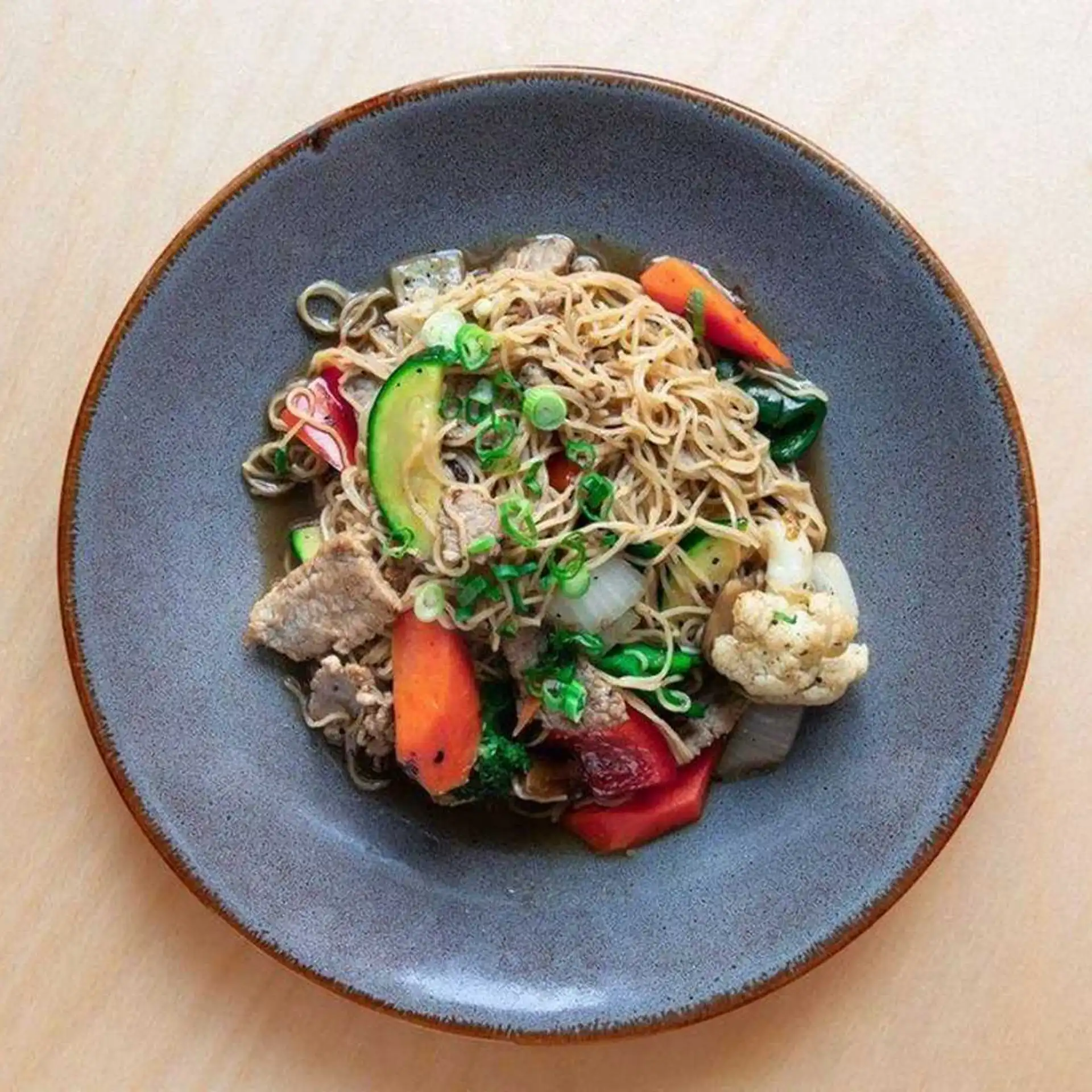 Nouilles aux œufs sautées avec bœuf et légumes assortis cuits dans une sauce Bati au gingembre.
