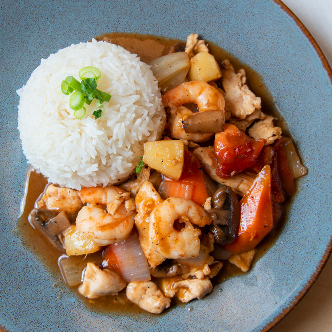 Sauté de crevettes et de poulet accompagné de morceaux d'ananas grillés dans une sauce aigre-doux.