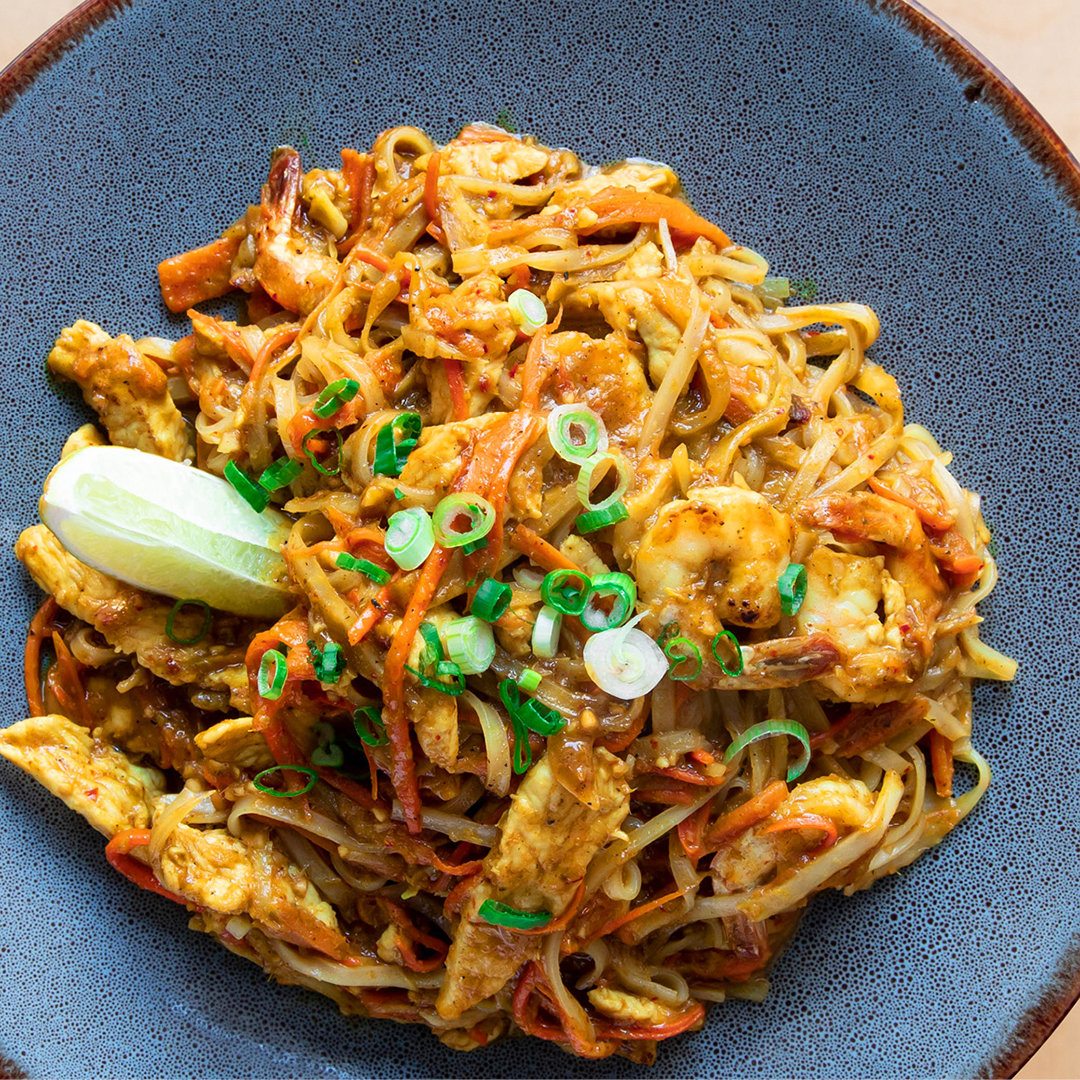 Nouilles de riz sautées avec poulet et crevettes au curry, germes de soja, carottes râpées et chou.