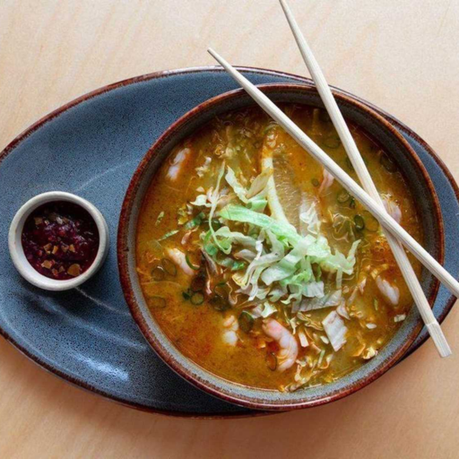 Soupe au curry et lait de coco avec du poulet, des vermicelles de riz et de la laitue.