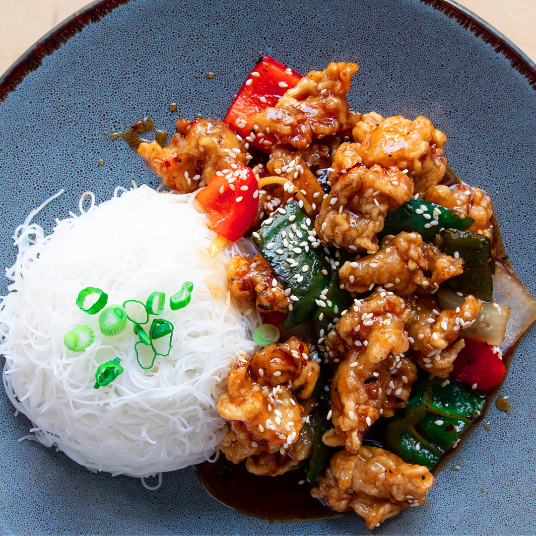 Le poulet classique General Tao de Bati, légèrement épicé, servi avec poivrons verts et rouges, oignons et sésame rôti.